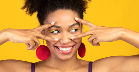 Happy afro girl showing v sign at orange studio