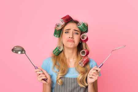 Girl spreads arms to sides, holds spatula and ladleの写真素材
