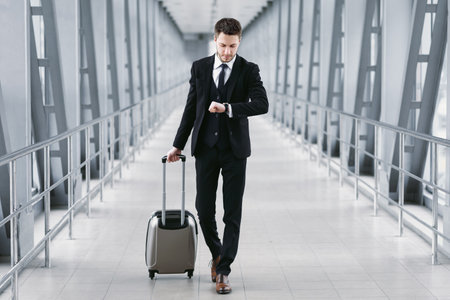 Adult business man standing in airport with suitcaseの写真素材