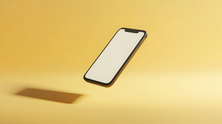 A smartphone floating against a vibrant yellow backdrop during bright, natural lightingの素材