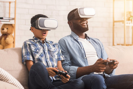 Afro Father And Son Trying VR Glasses At Home, Playing Videogamesの写真素材