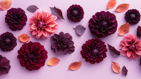 Beautiful arrangement of deep red and pink dahlias with leaves on a soft pastel backgroundの素材