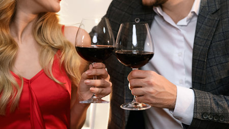 Couple clinking red wine glasses on romantic date in restaurant, closeupの写真素材
