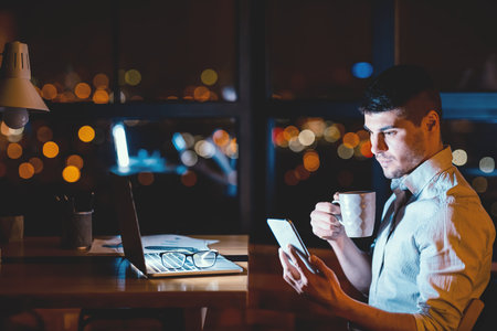 Businessman Using Smartphone Working Overnight In Officeの写真素材
