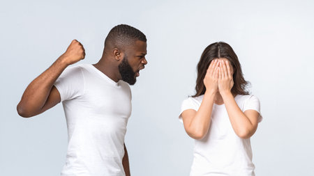 Afro man trying to hit his scared wife, raising fistの写真素材