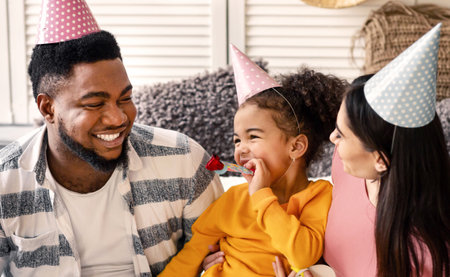 Multiracial family in caps blowing in fifesの写真素材