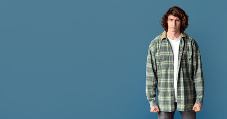 Young guy clenching his fists in anger and frowning on turquoise backgroundの写真素材