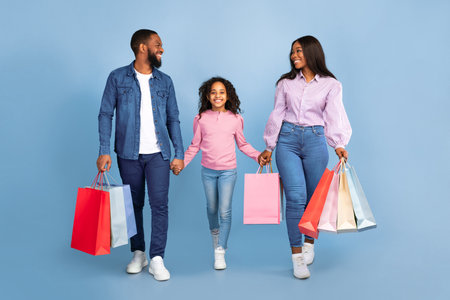 African American woman, man and girl walking with shopping bagsの写真素材