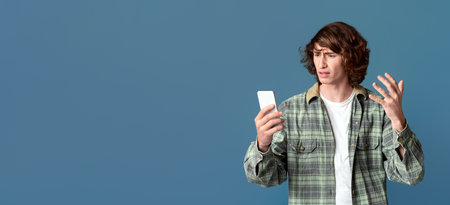 Annoyed teenager using cell phone for online chatting, turquoise background