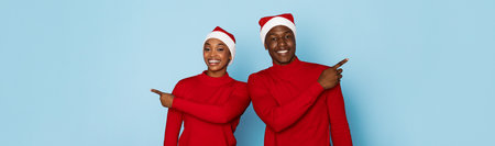 Cheerful couple in Santa hats poses against a blue backgroundの写真素材