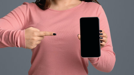 Young Woman In Medical Mask Pointing At Smartphone With Black Screenの写真素材