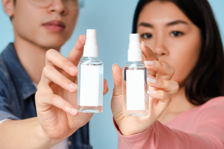 Hand sanitizer. Young asian couple showing bottles with antibacterial sprayの写真素材