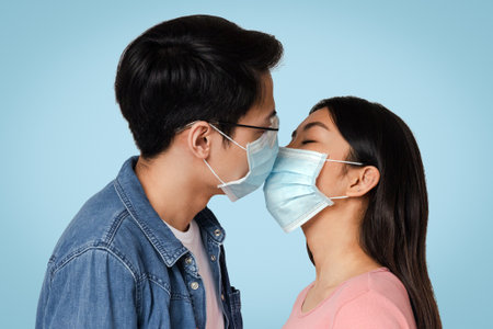 Romantic Young Chinese Couple Kissing In Protective Medical Face Masksの写真素材