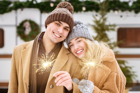 Couple celebrating winter with sparklers in snowy outdoor setting at duskの写真素材
