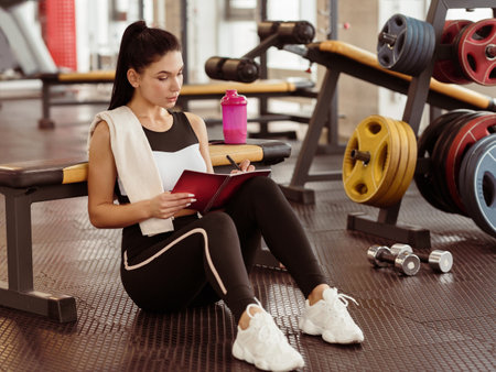 Beautiful woman making her training plan in sports clubの写真素材