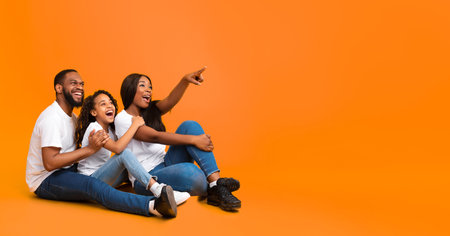 Smiling black family pointing aside at free copy spaceの写真素材