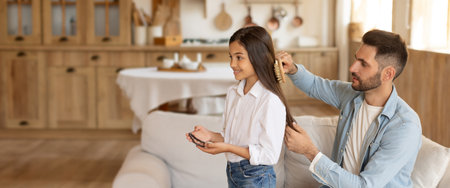 Father gently combs daughters long hair in a stylish home setting