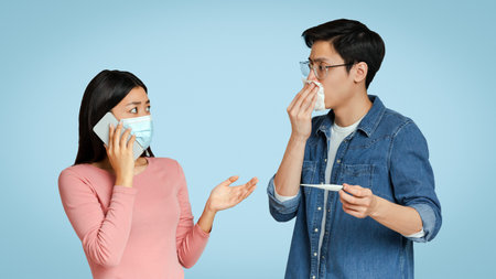 Coronavirus Anxiety. Asian Girl In Medical Mask Calling Ambulance For Sick Boyfriendの写真素材