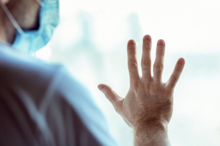 Man In Mask Looking Out Of Window Staying At Homeの写真素材