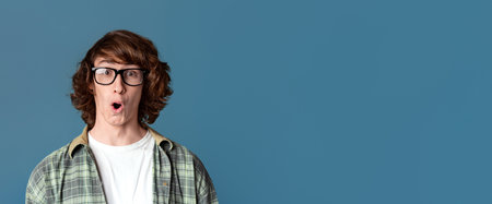 Shocked millennial guy with glasses on color background