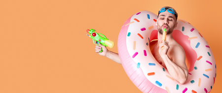 Guy in inflatable ring and glasses for swimming blowing in water gunの写真素材