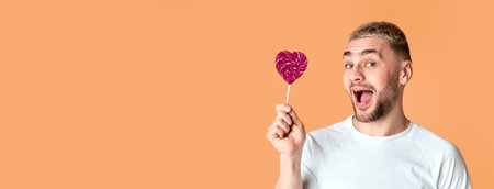 Emotional man with open mouth holds heart lollipopの写真素材