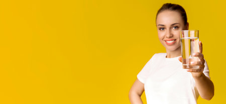 Glass of clean mineral water in hands of smiling young woman