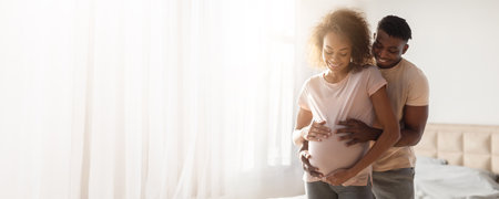 Expecting parents cherish intimate moment in bright, cozy bedroom settingの写真素材