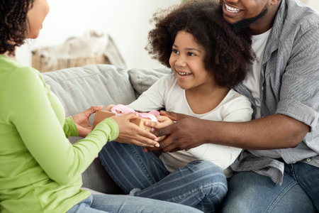 Birthday Concept. Happy Black Father And Daughter Giving Present To Surprised Momの写真素材