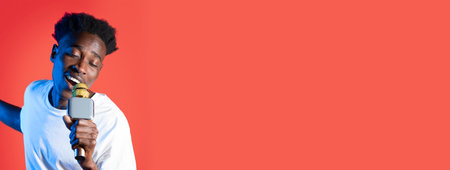 Young man singing passionately with a microphone in a vibrant settingの写真素材