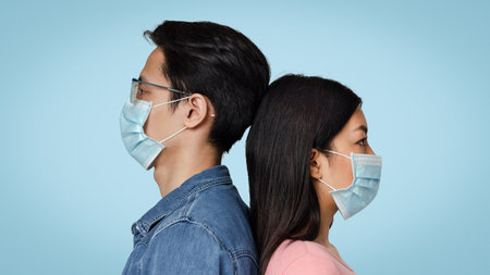 Virus Protection. Young Asian Couple Wearing Medical Masks Posing In Studioの写真素材