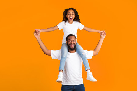 Cheerful African American Man Riding Excited Daughter On His Shouldersの写真素材