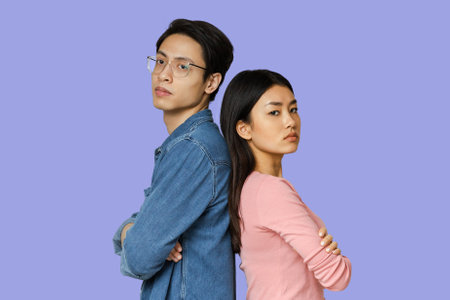 Unhappy asian man and woman staying back to backの写真素材