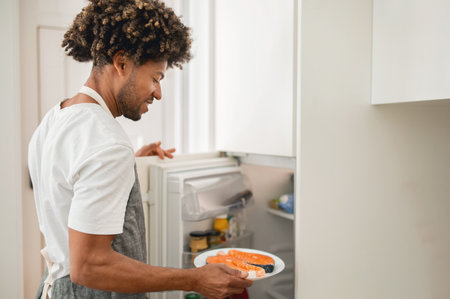 A man preparing a meal by taking ingredients out of the refrigerator at homeの写真素材