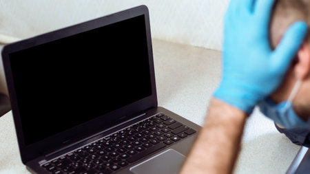 Entrepreneur At Laptop Cupping Head In Hands In Despair Indoorsの写真素材