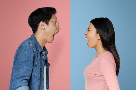 Asian man and woman shouting over grey backgroundの写真素材