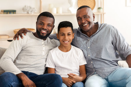 Portrait of smiling millennial black dad, son and grandfather at home