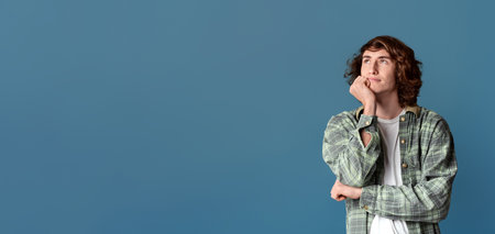 Attractive teenage guy deep in thought on turquoise background