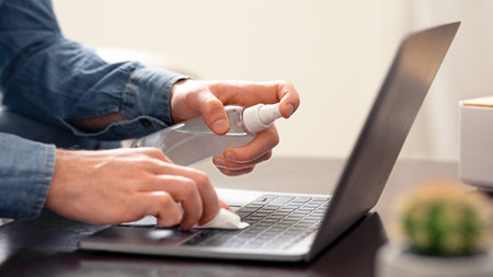 Man cleaning laptop keyboard with sanitizer, close upの写真素材