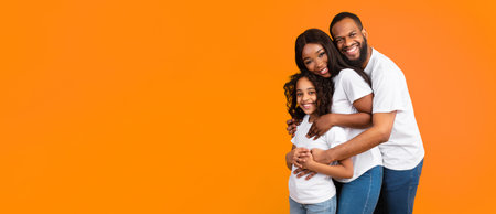 African American man hugging his wife and smiling daughter, panoramaの写真素材