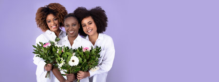 Three Cheerful African American Women Holding Flowers Over Purple Backgroundの写真素材