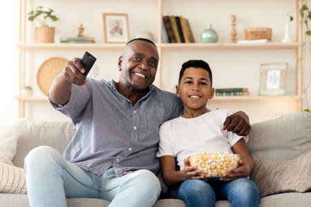 Happy african granddad and his grandson watching TV together at homeの写真素材