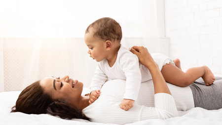 African Mom Lying With Baby On Stomach In Bedroom Indoor