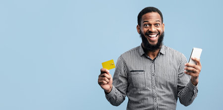 Black man holding credit card and cellphone at studio