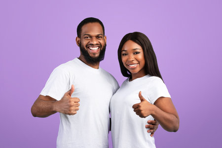 Happy black couple gesturing thumbs up, hugging and smiling, bannerの写真素材