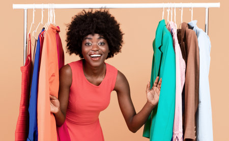 Black Shopaholic Lady On Shopping Posing With Clothing Rail, Studioの写真素材