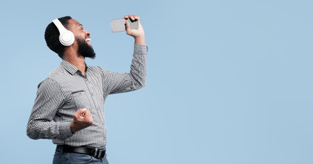 Afro man singing using smartphone as microphoneの写真素材