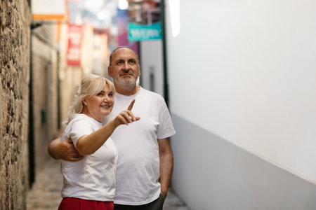 Happy couple enjoying a stroll through a charming narrow street in the afternoonの写真素材