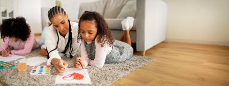 Mother and daughters enjoy creative time together while painting at homeの写真素材