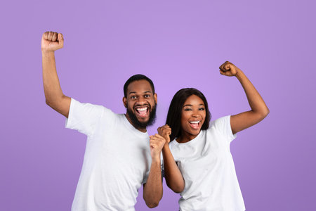 Portrait of emotional black couple screaming with raised fistsの写真素材